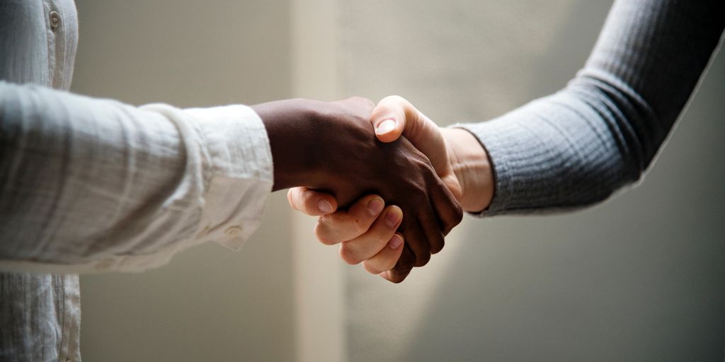 real estate agent shaking hands with client in front of a house in Vernon