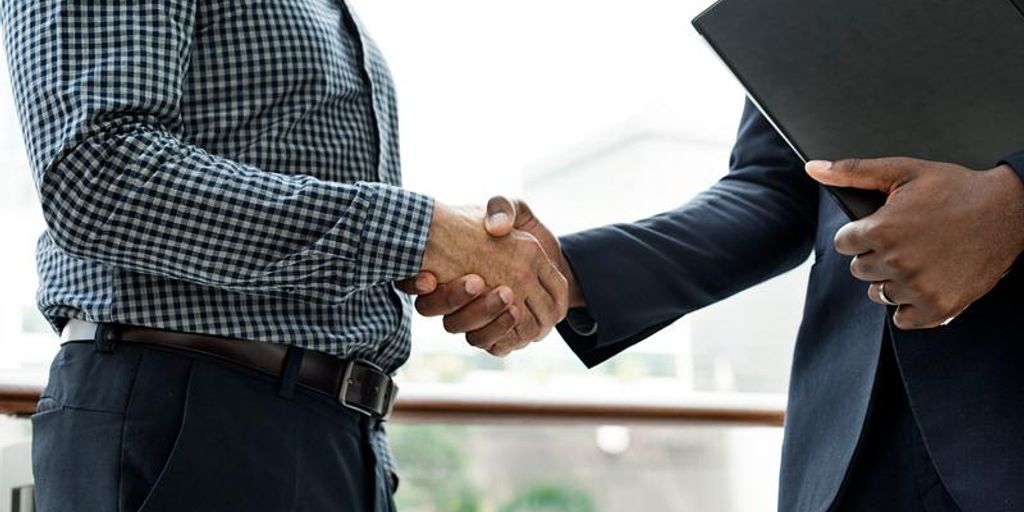 real estate agent shaking hands with client in front of house for sale in Commerce