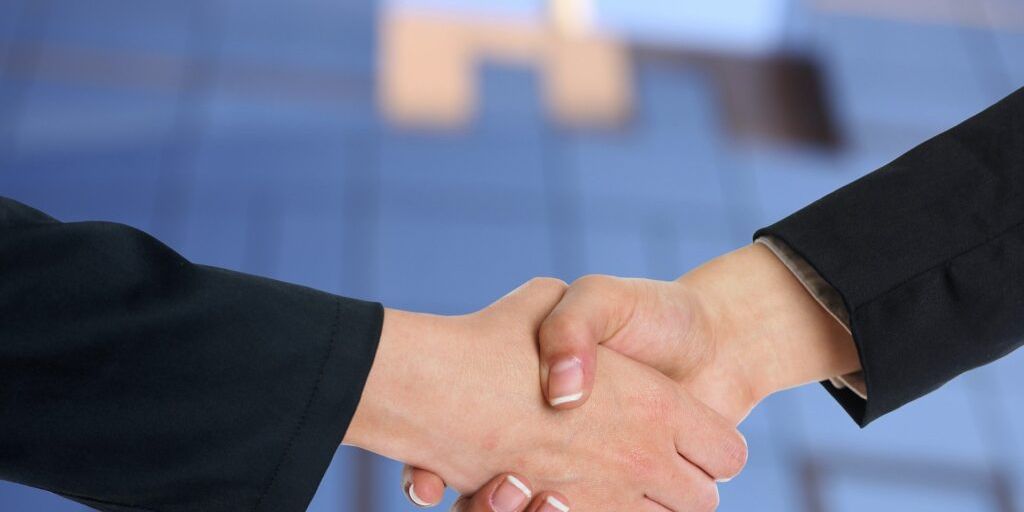 real estate agent shaking hands with client in front of house in San Marcos